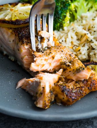 Close up shot of herb crusted broiled salmon being flaked with a fork