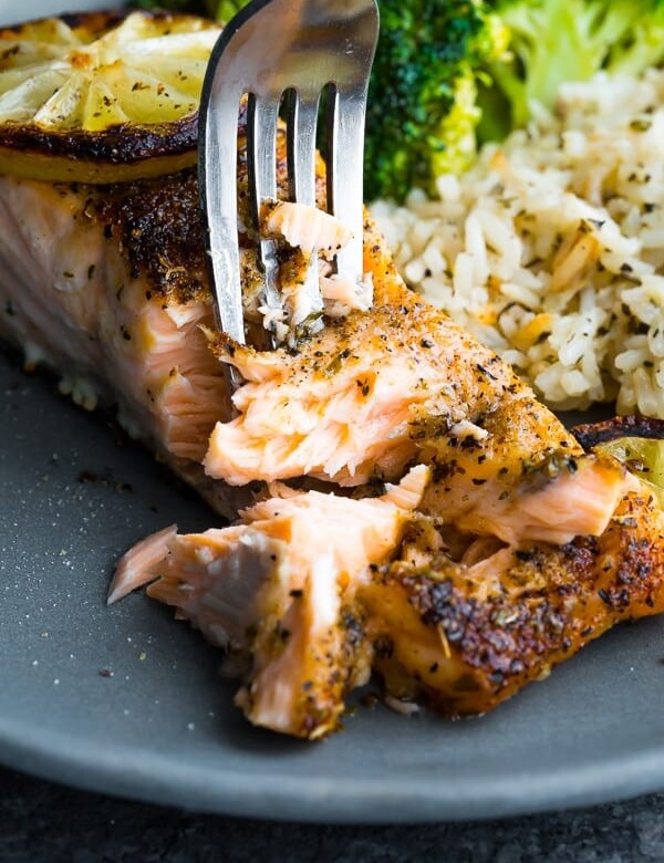 Close up shot of herb crusted broiled salmon being flaked with a fork