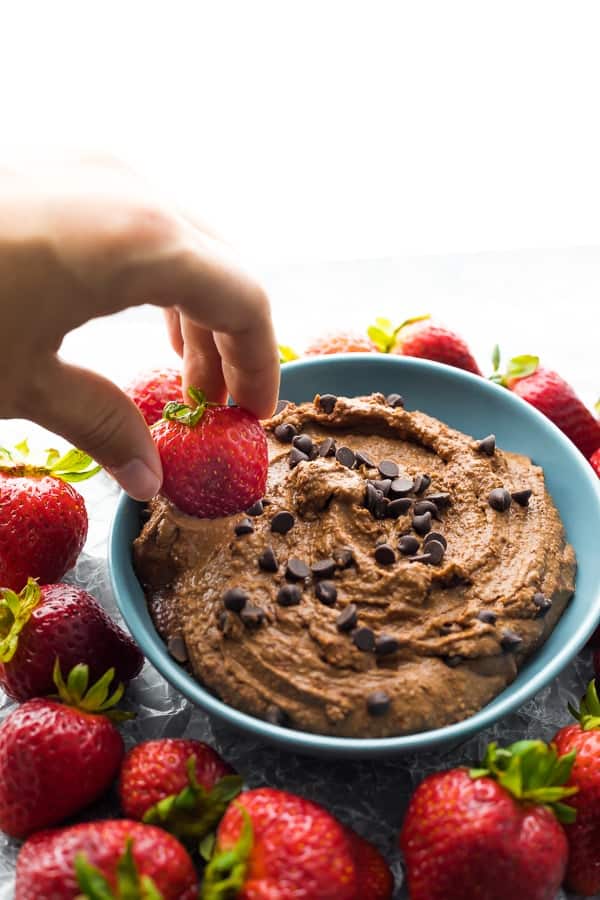 dipping a strawberry into the brownie batter hummus