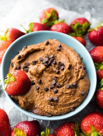 Creamy chocolate dessert hummus in blue bowl with chocolate chips and fresh strawberries