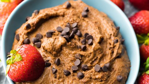 Creamy chocolate dessert hummus in blue bowl with chocolate chips and fresh strawberries