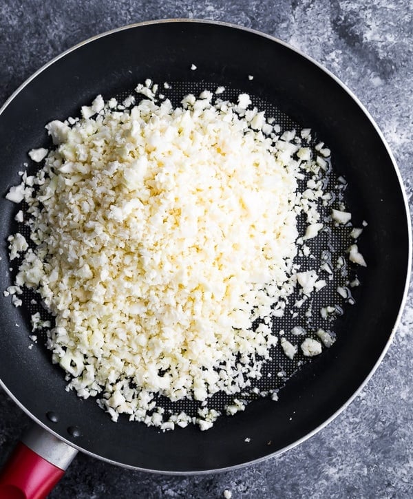 showing how to cook cauliflower rice in a frying pan