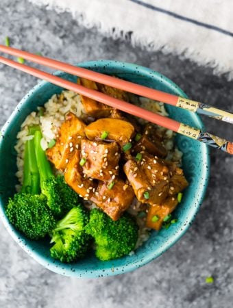 overhead shot of teriyaki chicken with broccoli in blue bowl and chopsticks