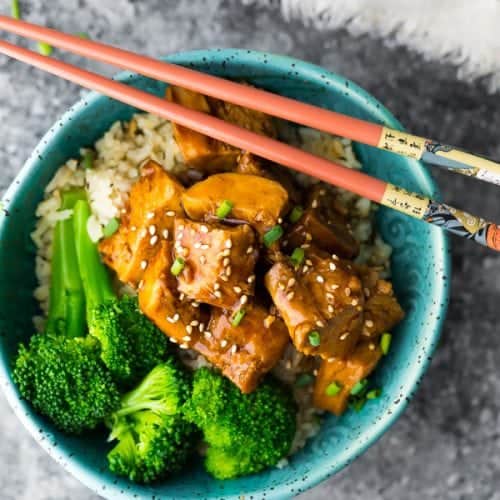 overhead shot of teriyaki chicken with broccoli in blue bowl and chopsticks