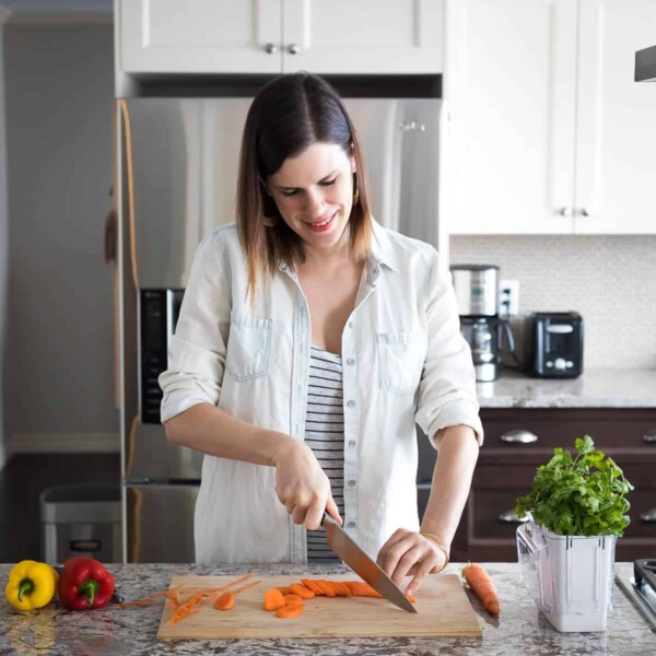 Denise standing at her kitchen cutting carrots on a wood board