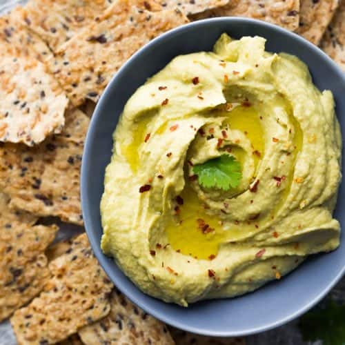 overhead shot of avocado hummus in a gray bowl with tortilla chips
