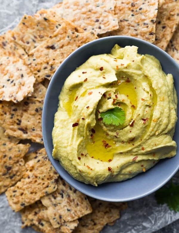 overhead shot of avocado hummus in a gray bowl with tortilla chips
