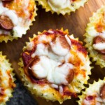 overhead shot of multiple cauliflower pizza muffins on wood board