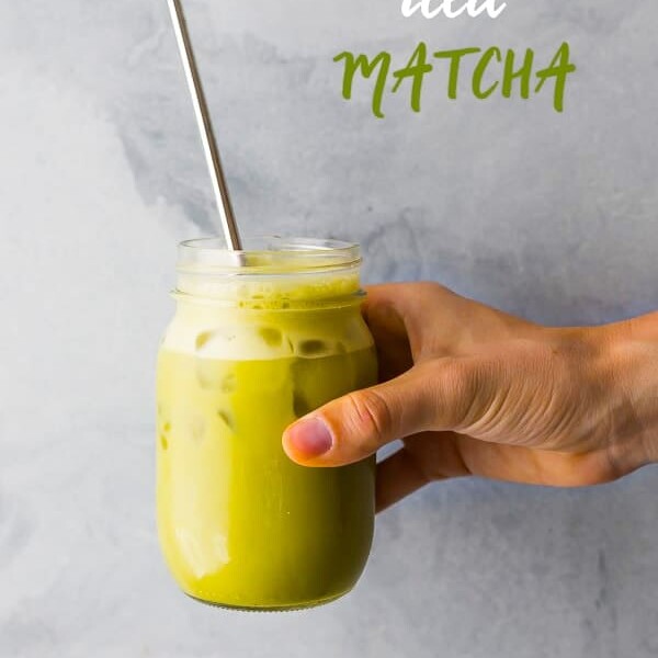 hand holding an iced matcha latte with straw
