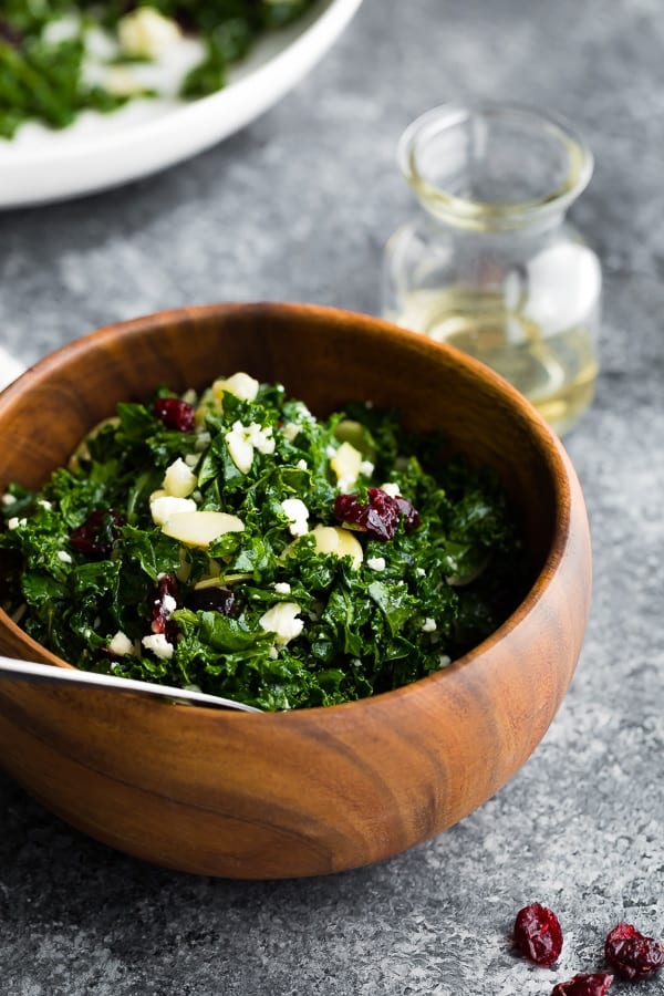 kale salad with cranberries in wooden bowl