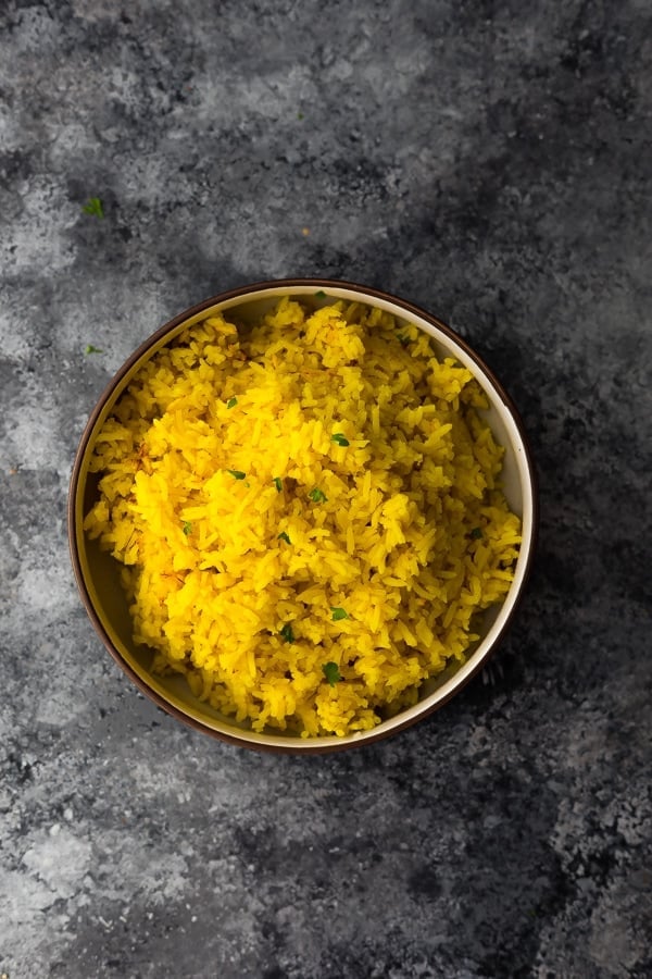 bowl with turmeric yellow rice on grey background