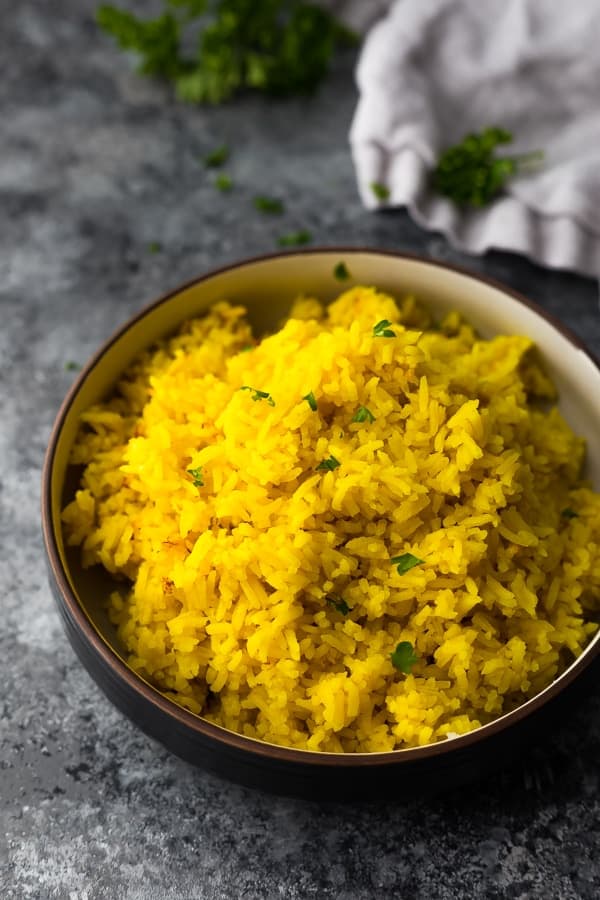 bowl with turmeric yellow rice on grey background