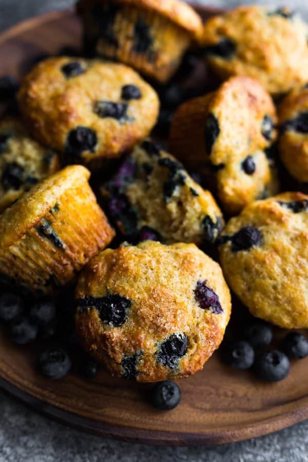 A pile of healthy blueberry muffins with fresh blueberries in bowl