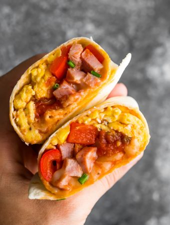 hand holding breakfast burrito cut in half