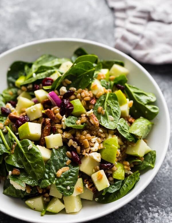 white bowl filled with autumn apple farro salad on gray background