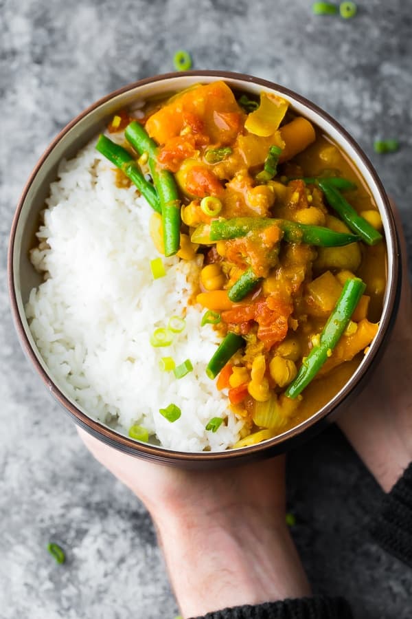 hands holding a bowl of chickpea curry cooked in the instant pot
