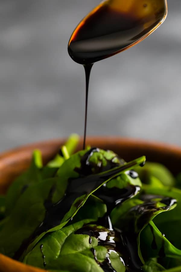 drizzling the balsamic reduction onto a salad