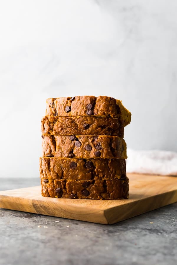 healthy chocolate chip pumpkin bread slices stacked on a cutting board
