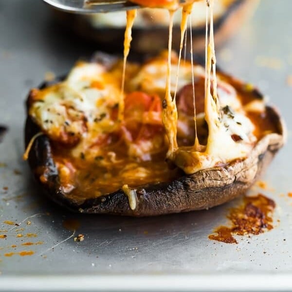 close up shot of pepperoni pizza stuffed portobello mushroom with fork lifting up melted cheese