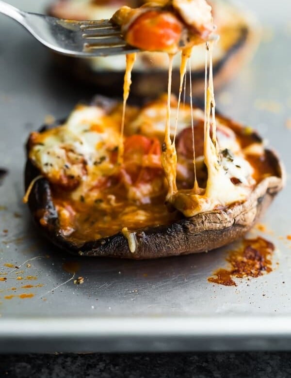 close up shot of pepperoni pizza stuffed portobello mushroom with fork lifting up melted cheese