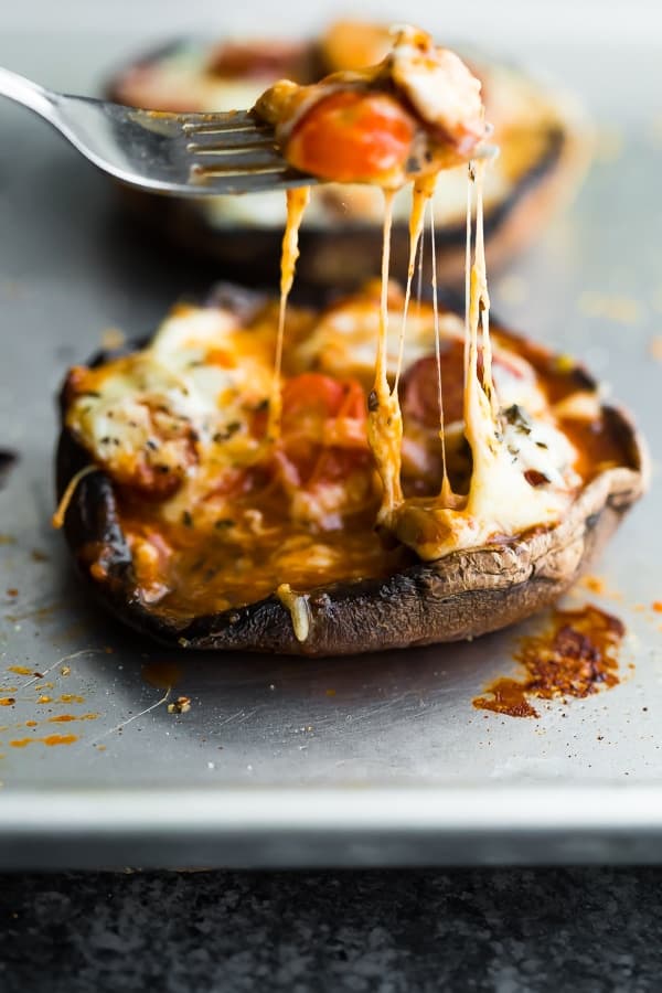 fork pulling melted cheese up from a pepperoni pizza stuffed portobello mushrooms