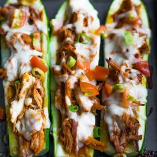 three pulled pork stuffed zucchini boats in a row
