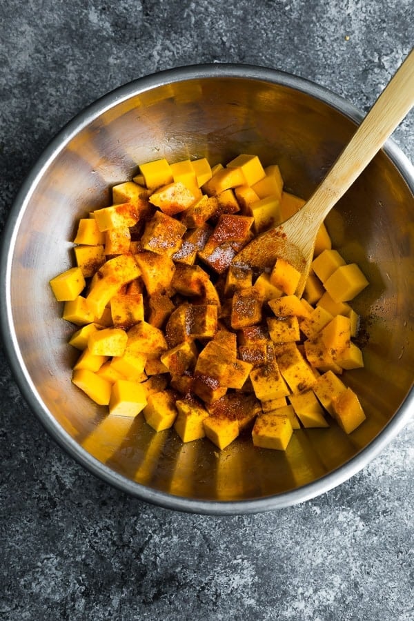 how to roast butternut squash- tossing the butternut squash cubes with spices and oil