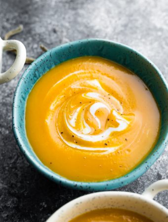 butternut squash soup in blue bowl on gray background