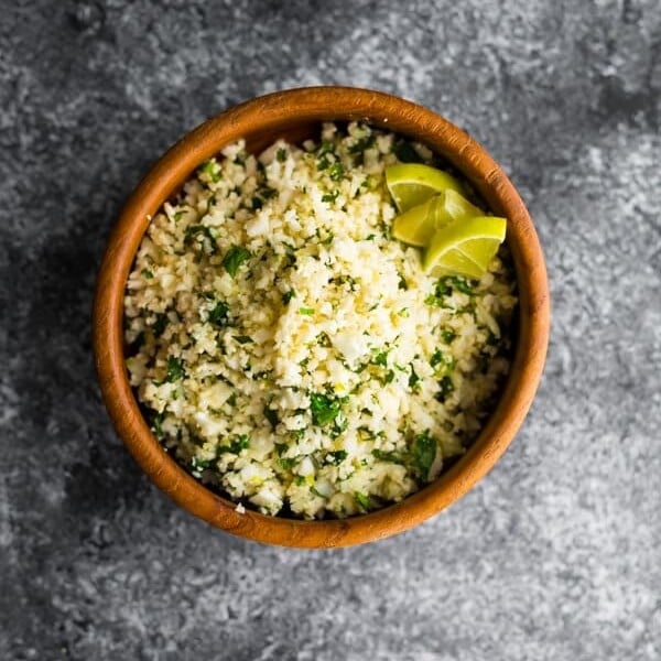 overhead shot of cilantro lime cauliflower rice in wood bowl on gray background