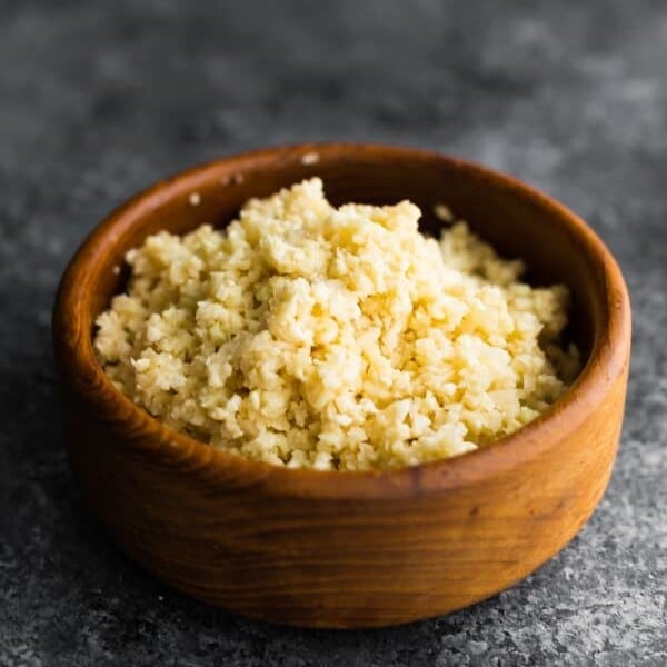 side view of coconut cauliflower rice in wood bowl on gray background