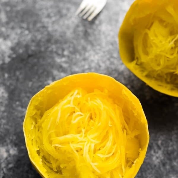 cooked spaghetti squash cut in half with a fork in the background