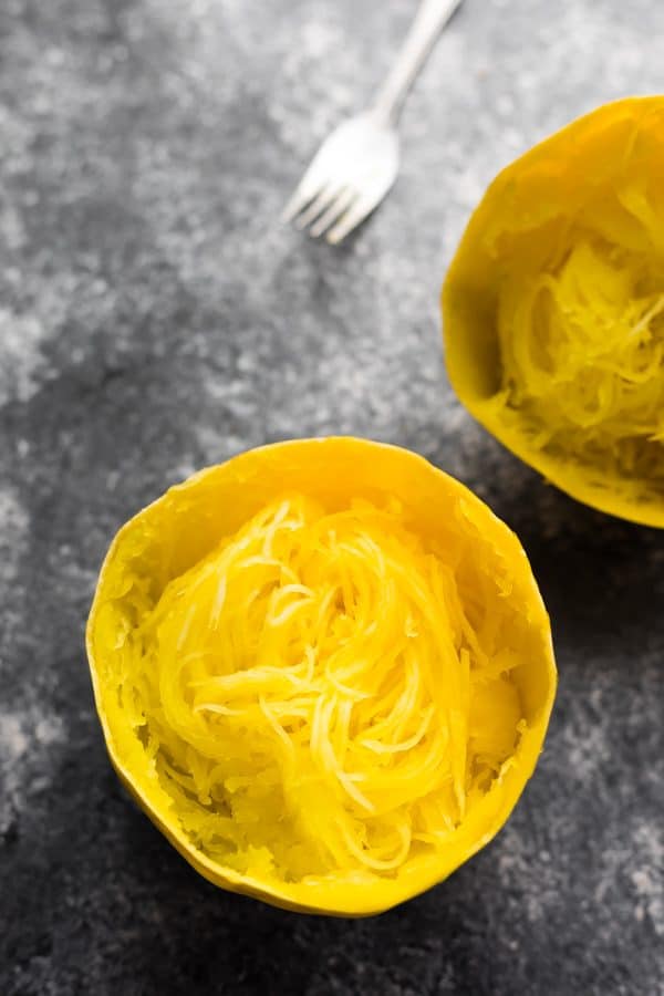 cooked spaghetti squash cut in half with a fork in the background