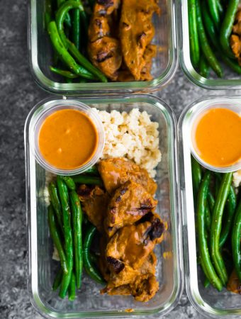 overhead shot of satay beef with green beans in four glass meal prep containers