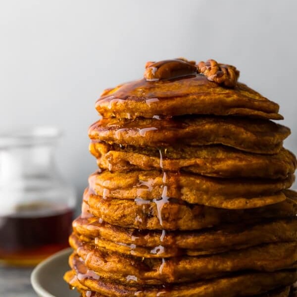 large stack of pumpkin pancakes with pecans on top