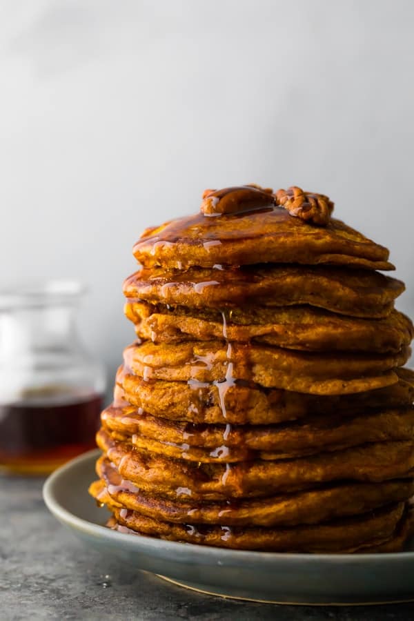 a stack of the pumpkin pancakes recipe with syrup drizzling