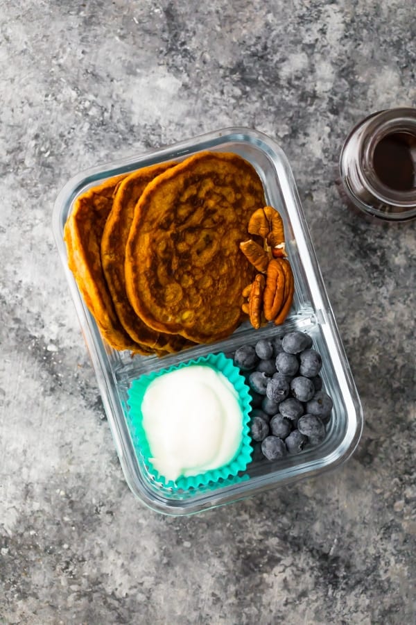 pumpkin spice pancakes in a meal prep container with yogurt, pecans and berries