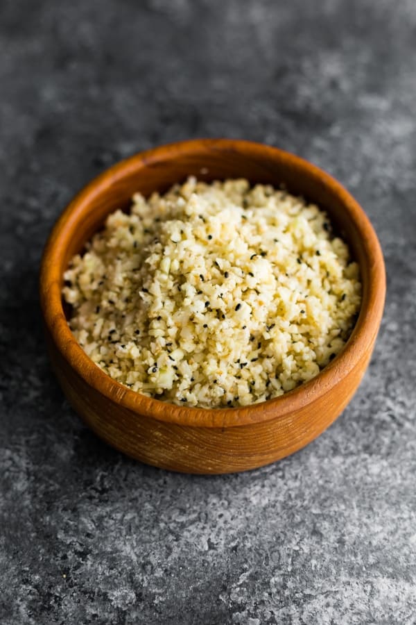 sesame ginger cauliflower rice in wood bowl on gray background