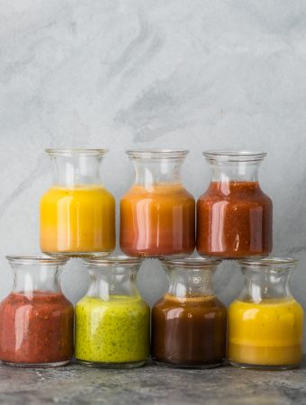 a stack of 7 glass jars filled with various vinaigrette recipes