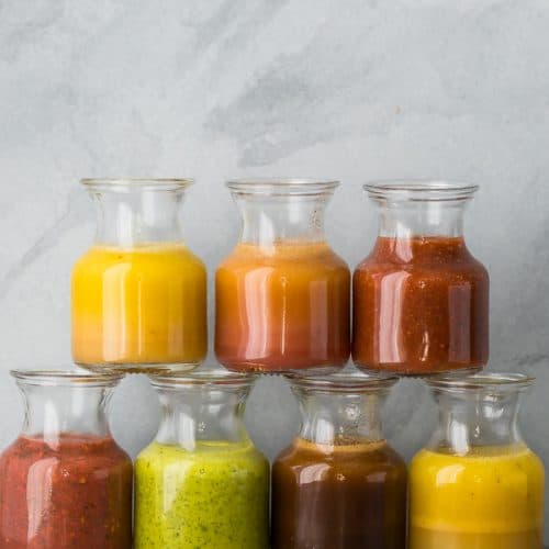 a stack of 7 glass jars filled with various vinaigrette recipes