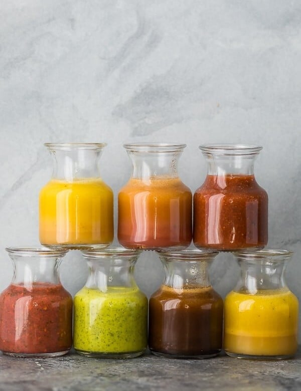 a stack of 7 glass jars filled with various vinaigrette recipes