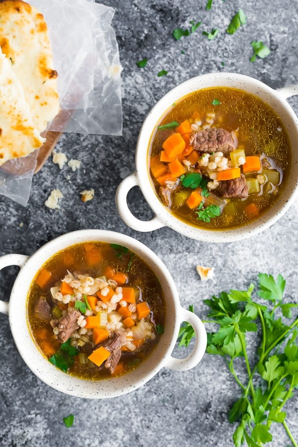 overhead view of beef barley soup in two white bowls