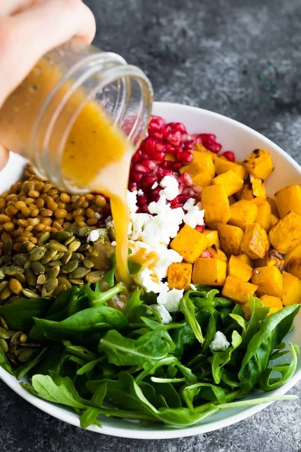 salad dressing being poured over harvest lentil salad