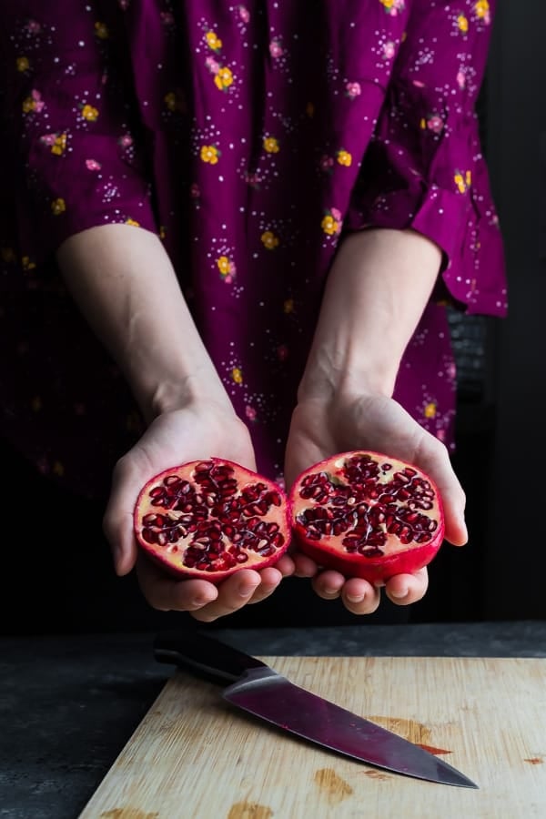 hands holding two pomegranate halves for how to cut a pomegranate