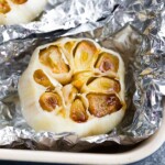 overhead shot of roasted head of garlic in aluminum foil