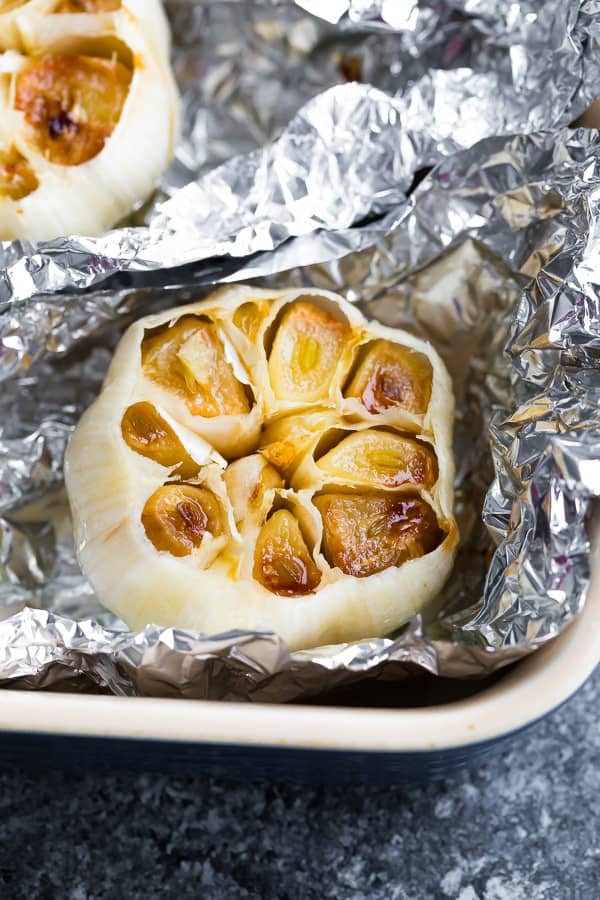 overhead shot of roasted head of garlic in aluminum foil