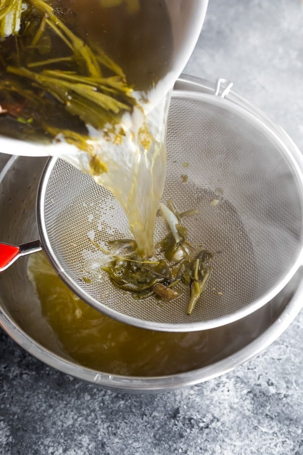 pouring the homemade bone broth through a colander