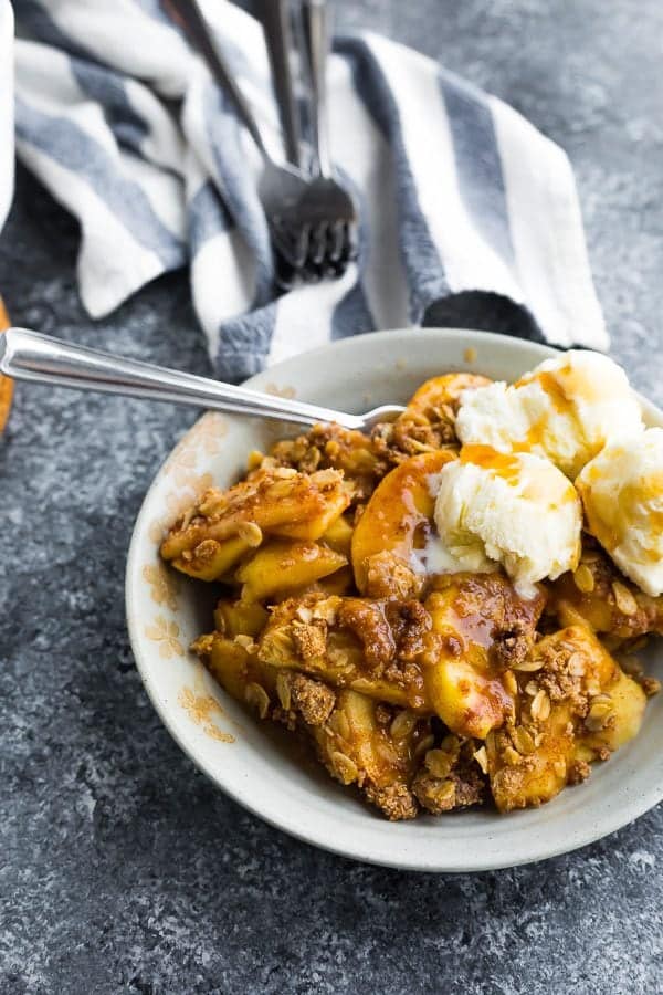 make ahead apple crisp in a white bowl with ice cream and a spoon