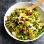 overhead shot of large white bowl filled with shaved brussels sprouts salad with pomegranates
