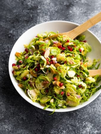overhead shot of large white bowl filled with shaved brussels sprouts salad with pomegranates
