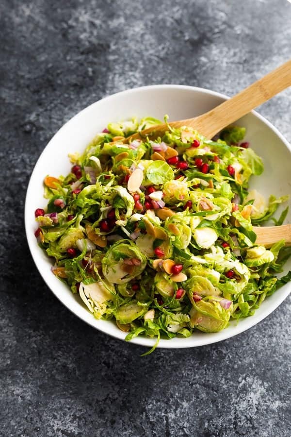 overhead shot of large white bowl filled with shaved brussels sprouts salad with pomegranates